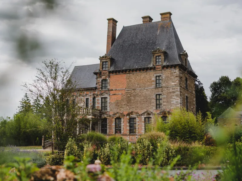 Château de Montgommery à Ducey-lès-Chéris (Manche), façade en brique et pierre du XVIIe siècle vue depuis le jardin fleuri