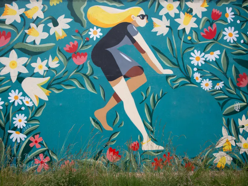 Fresque murale de Pierre Burnel à Parigny représentant une cycliste au milieu de fleurs sur fond turquoise