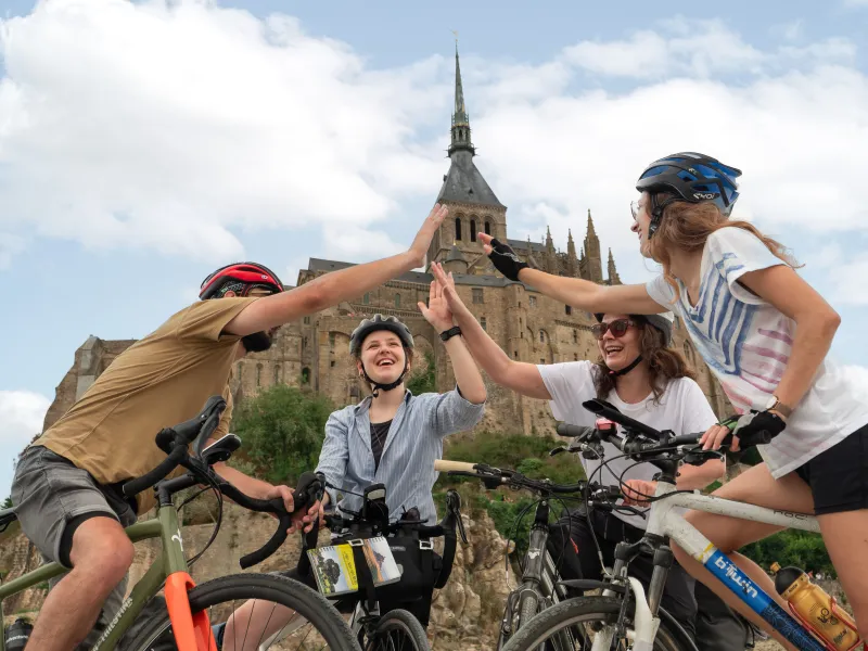 Cyclistes célébrant leur arrivée au pied du Mont Saint-Michel