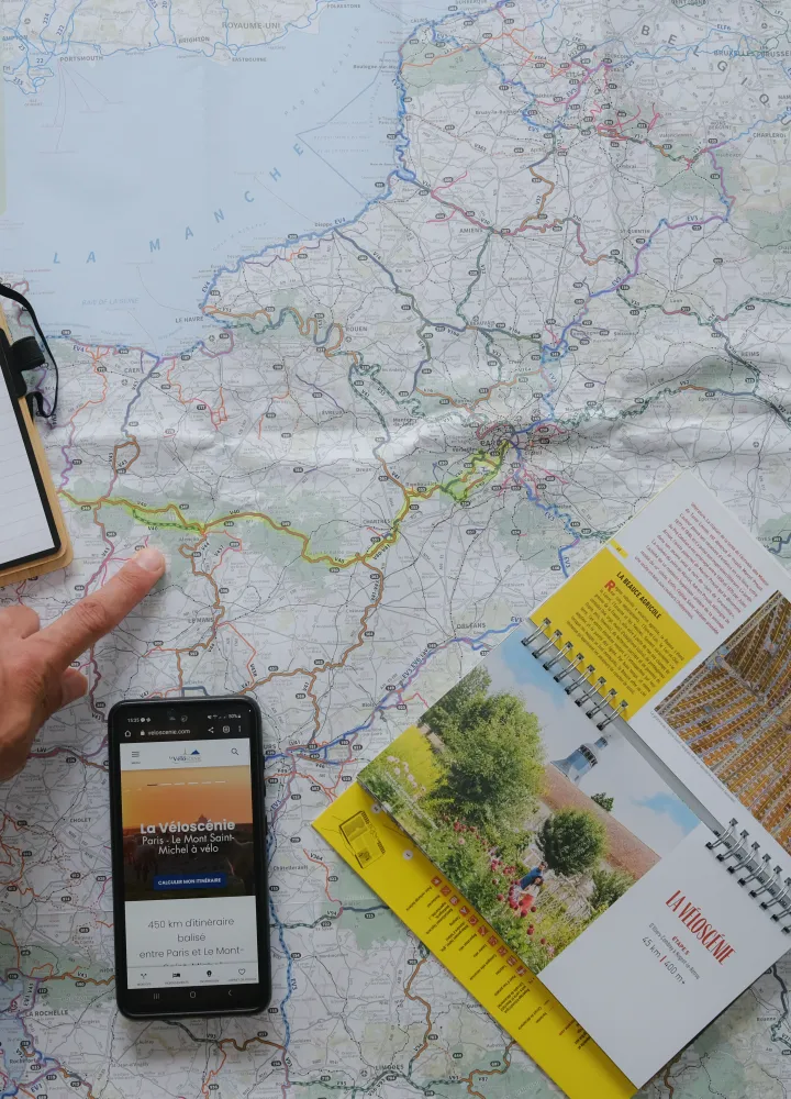 Carte, topoguide de la Véloscénie et smartphone posée sur une table