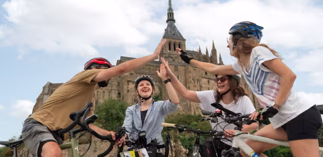 Cyclistes se tapant dans la main au pied du Mont Saint-Michel