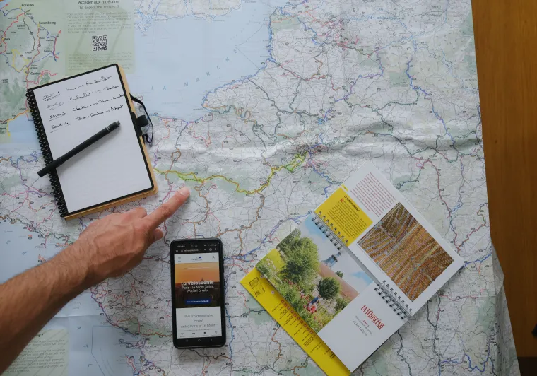 Carte, topoguide de la Véloscénie et smartphone posée sur une table