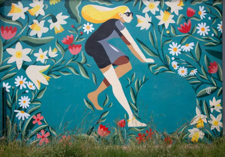 Fresque murale de Pierre Burnel à Parigny représentant une cycliste au milieu de fleurs sur fond turquoise