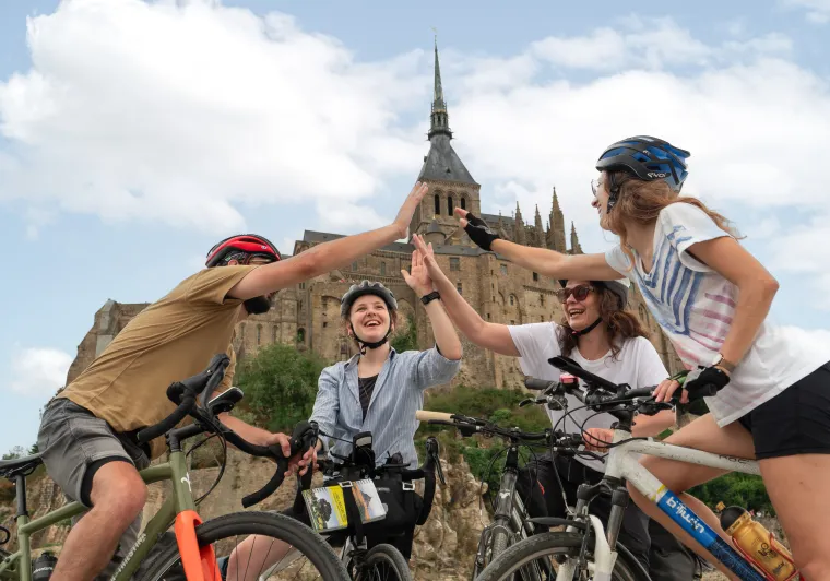Cyclistes se tapant dans la main au pied du Mont Saint-Michel