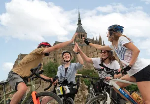Cyclistes se tapant dans la main au pied du Mont Saint-Michel