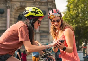 Deux cyclistes consultant leur itinéraire sur smartphone devant la fontaine Saint-Michel à Paris, au départ de La Véloscénie vers le Mont-Saint-Michel